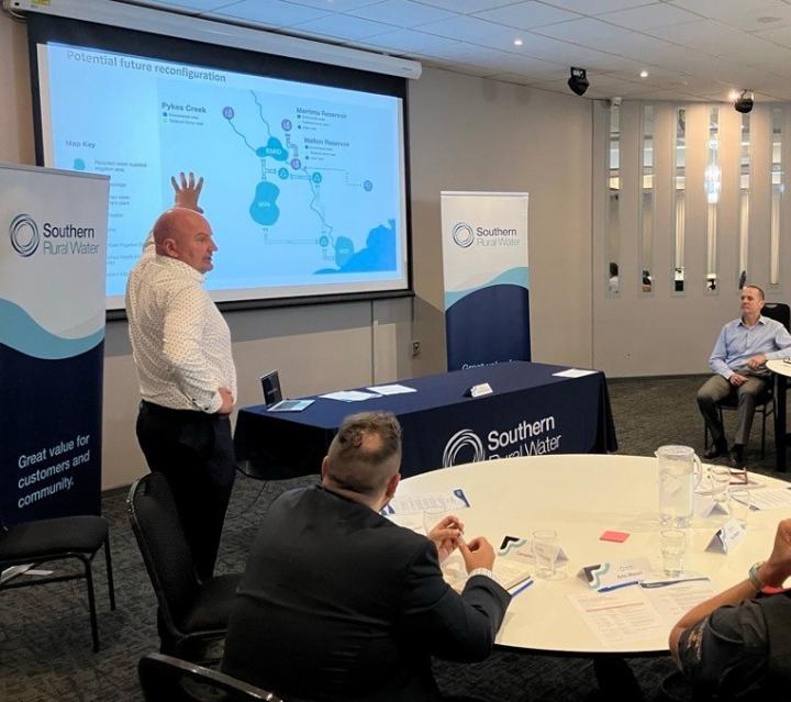 Man standing in front of projector screen presenting to a room of people