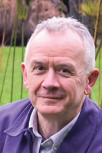 Headshot of smiling man in front of a green field 