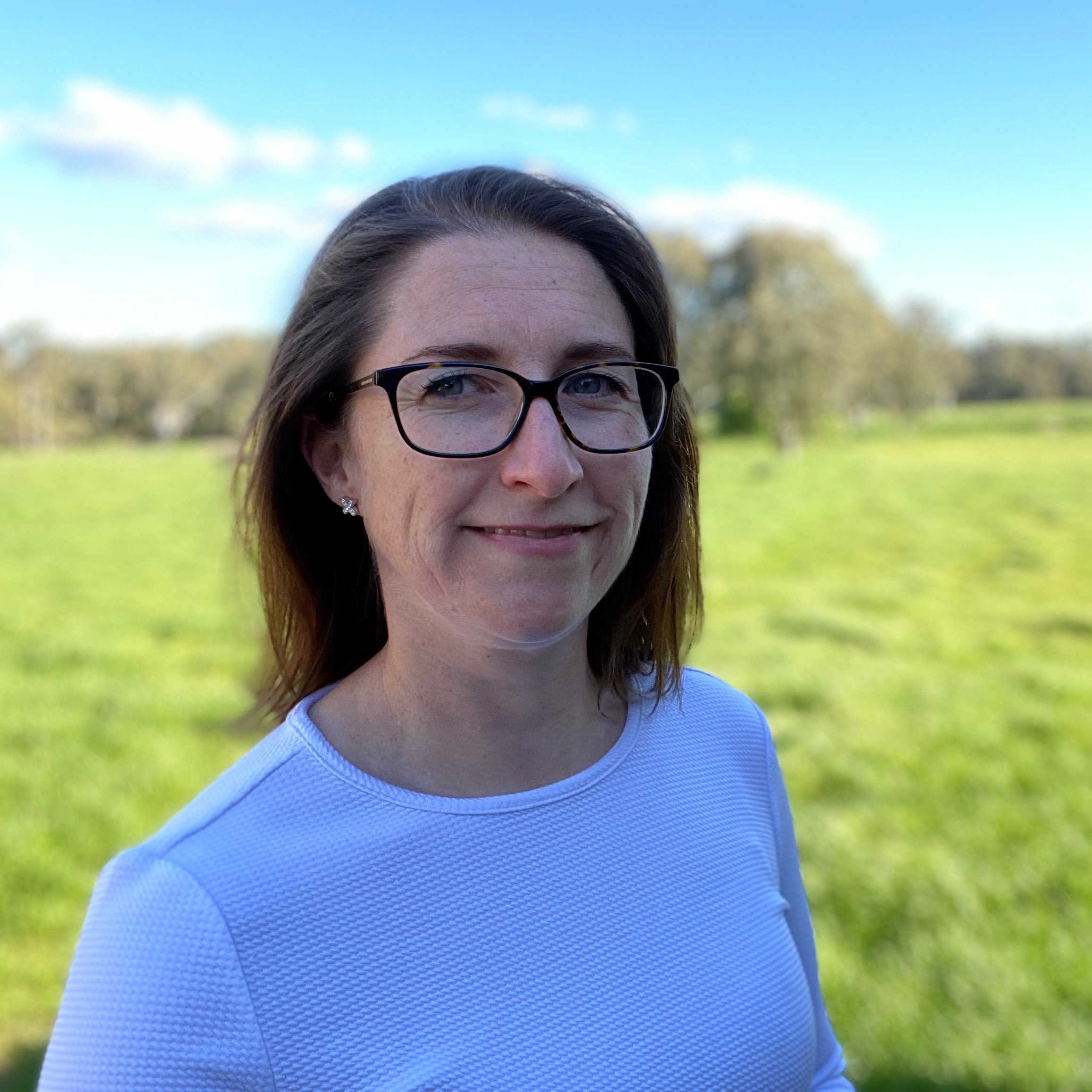 Smiling woman standing in front of a green field