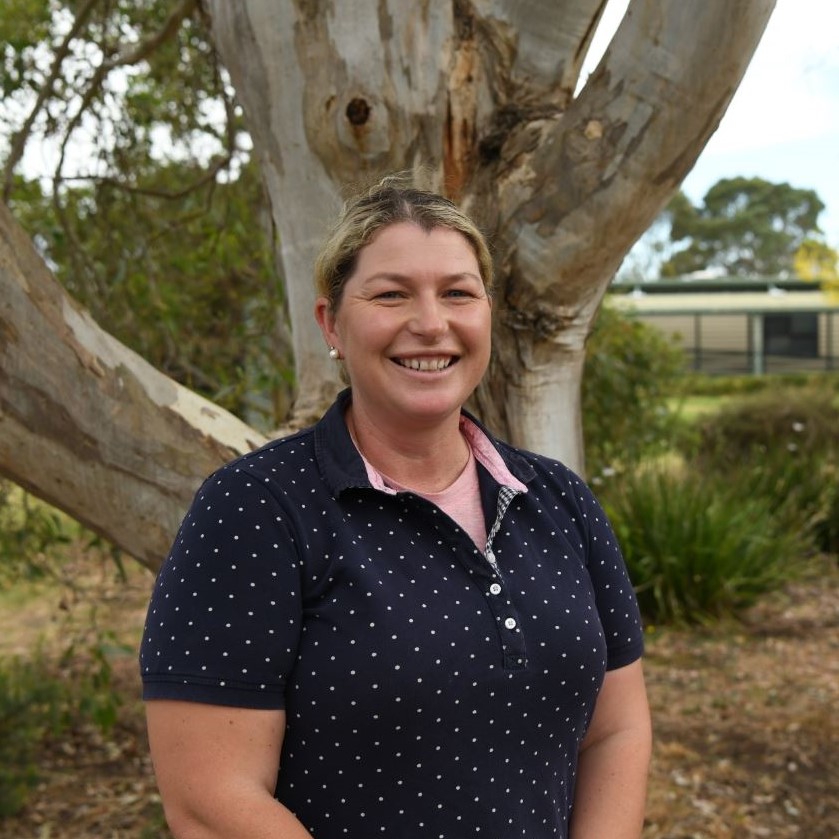 Smiling woman standing in front of large tree