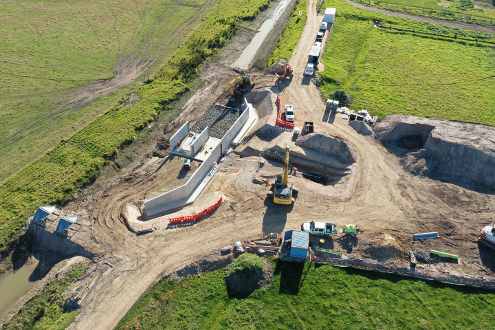 Birds eye image of construction vehicles in a field digging a hole
