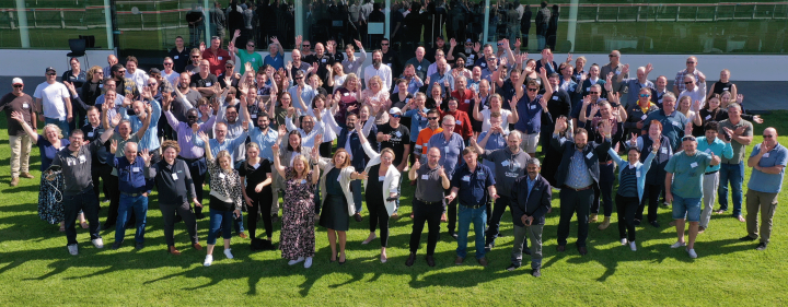A large group of people smiling with their hands up in celebration