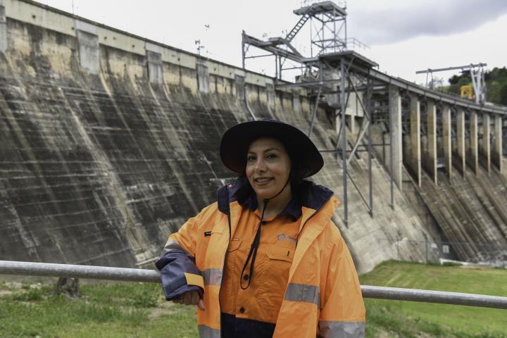 Woman in high vis standing in front of a dam wall