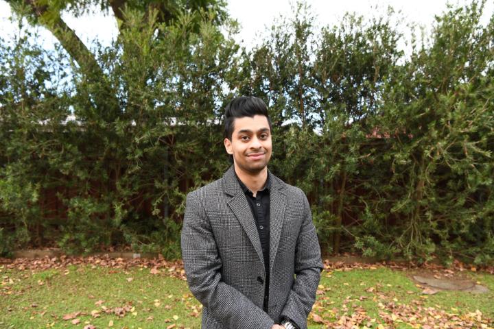 Man smiling while standing outside in front of trees