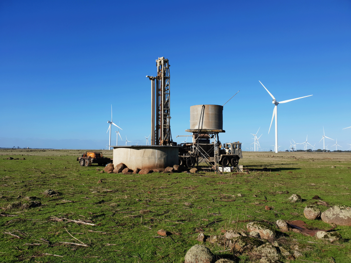 Water tank and trough on a farm with wind turbines in the background