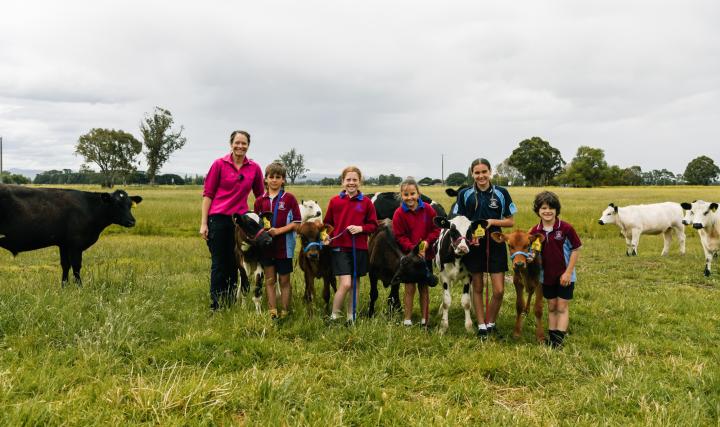 Kids standing with baby cows in a group photo, on a farm