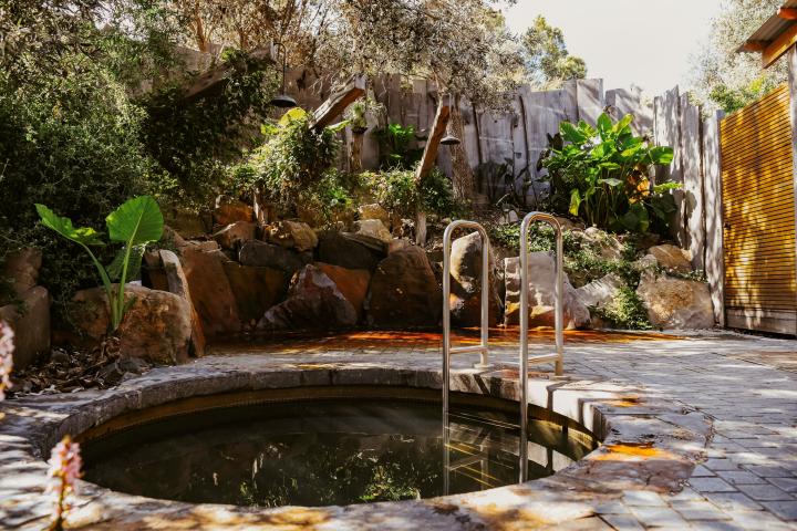 A small pool set in a peaceful setting with stone tiles and lush trees surrounding the pool.