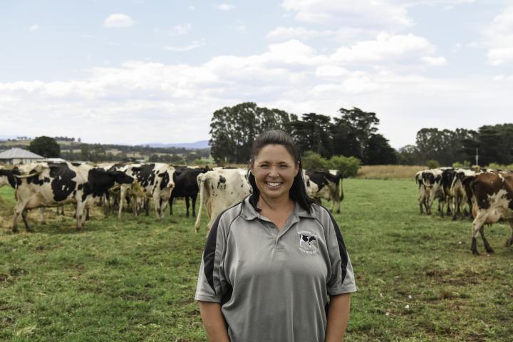 Woman standing among cows in a paddock eating grass