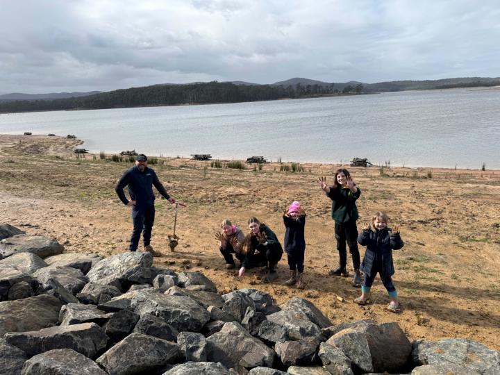 image of people by a lake planting small trees