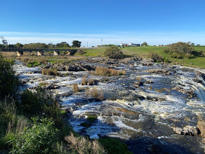 River flowing through rocks under a concrete bridge
