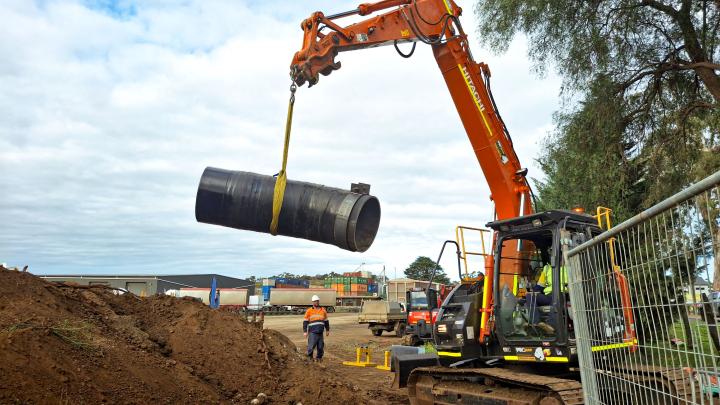 Pipe being lifted into air by excavator on a work site