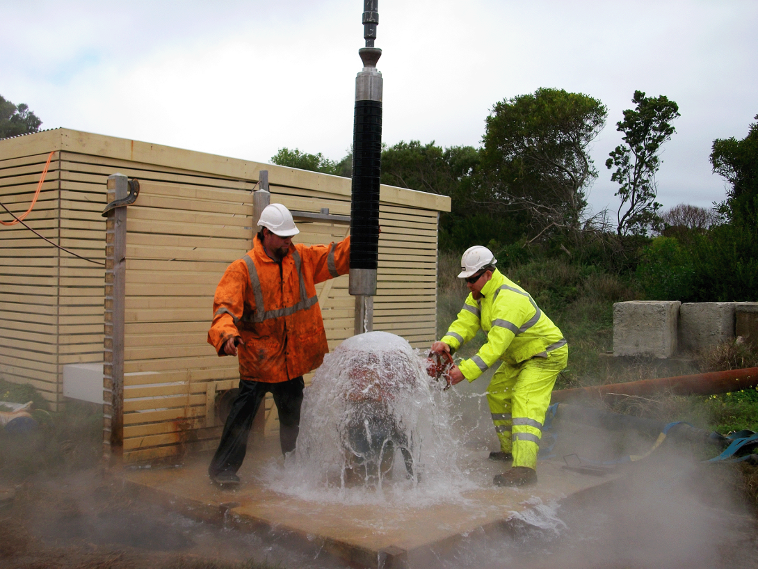 Two men in high vis repairing a bore